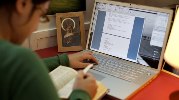 femme travaillant sur ordinateur avec photo de Sainte Rita.